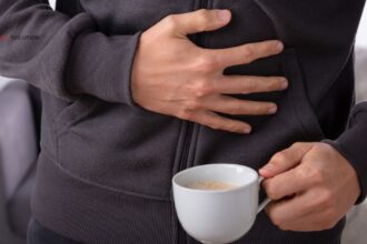 Person holding stomach in pain after drinking coffee